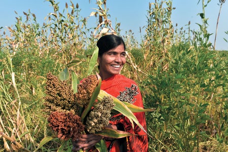 Woman in a field smiling while holding produce.