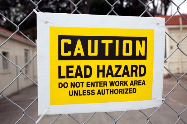 CAUTION LEAD HAZARD sign attached to chain link fence