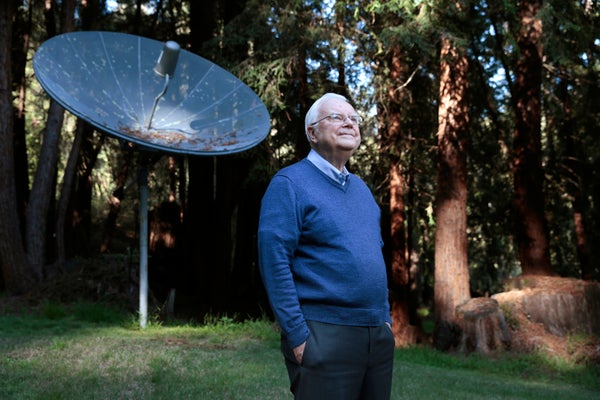 Frank Drake stands in front of a small satellite dish.