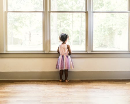 Preschool age girl looking out window.