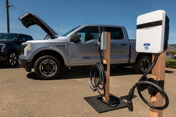 A white Ford Lightning F-150 pickup truck next to a charging station