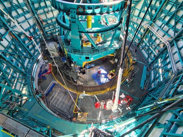 An enormous cylindrical structure rises from the floor of an observatory dome.