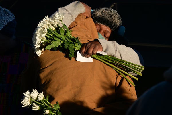 A person holding white roses embraces another