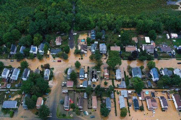 Aerial view of homes in flooded streets with trees in backgroun.