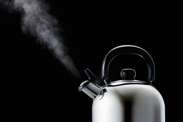 Still life of metal steaming kettle shown against a black backdrop.