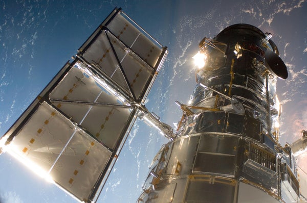 Hubble Space telescope with Earth in distance.