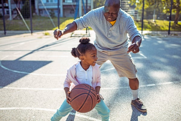 Grandfather and granddaughter playing basketball.