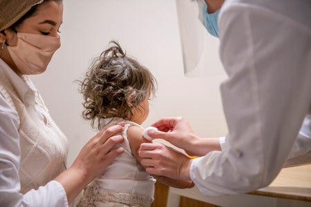 Rear view of toddler with doctor and nurse.