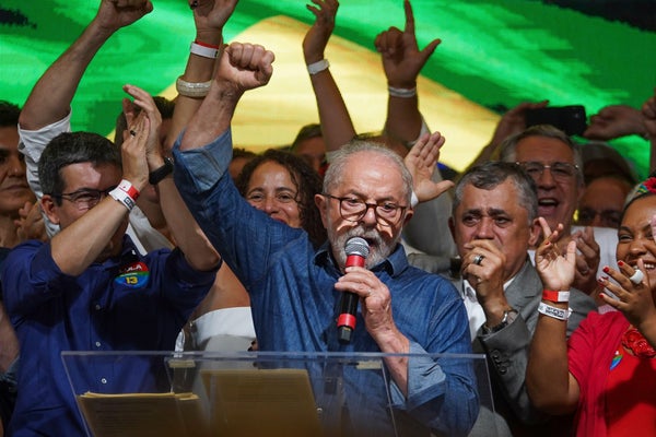 Luiz Inacio Lula da Silva raises his fist during his first speech while surrounded by supporters.
