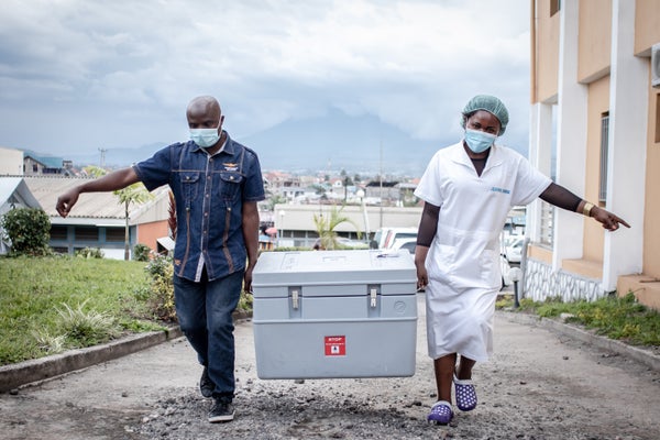 Two health care workers in Goma, Democratic Republic of the Congo, carrying a box with vaccination supplies.