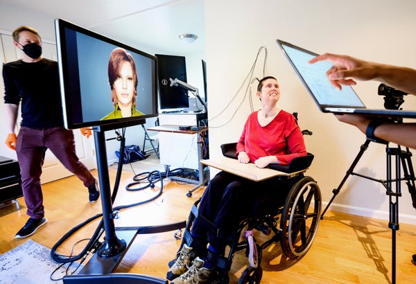 A research participant of speech neuroprostheses (red shirt in wheelchair), is connected to computers that translate her brain signals as she attempts to speak into the speech and facial movements of an avatar