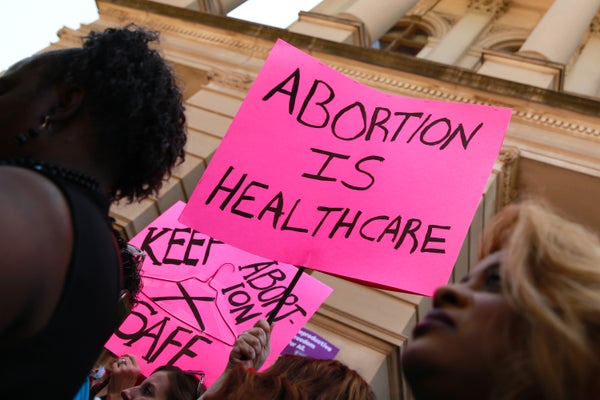 People hold signs during a protest against recently passed abortion ban bills.