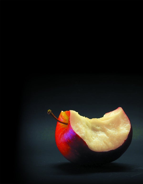 Half eaten red apple against dark background.