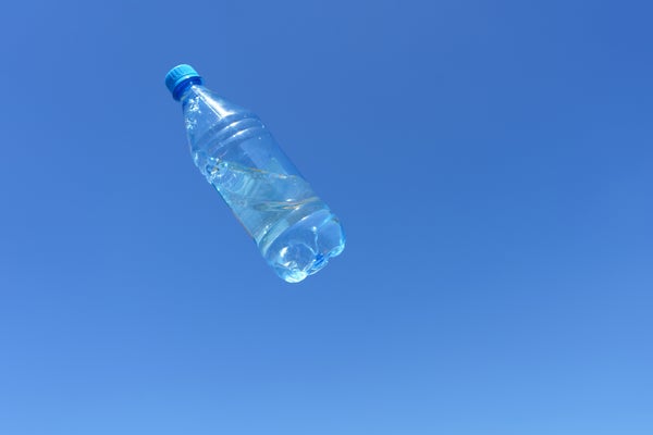 Plastic water bottle moving through the air against a blue sky