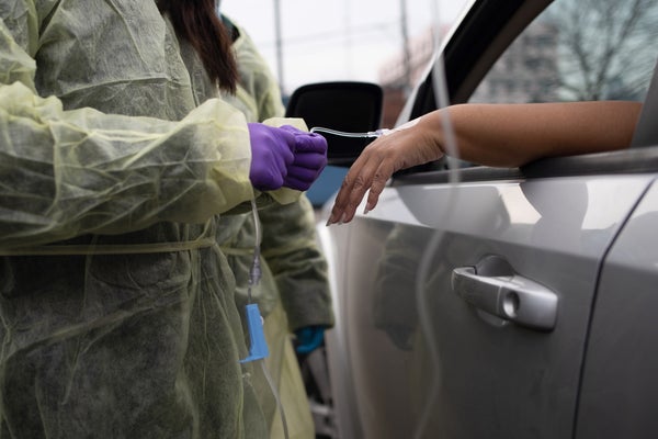Health care worker gives a patient an IV infusion in her car.