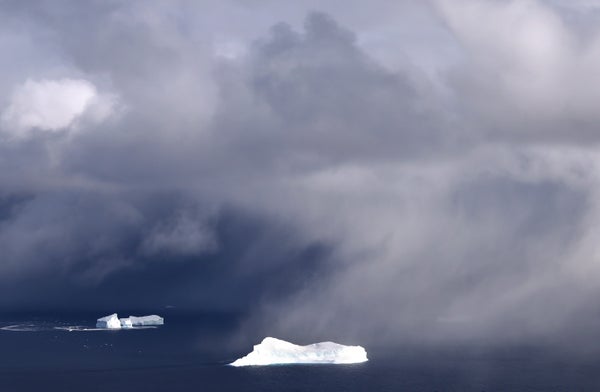 Icebergs seen floating under low clouds.
