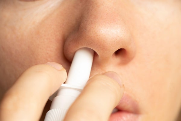 Close up of a person's nose using nasal spray