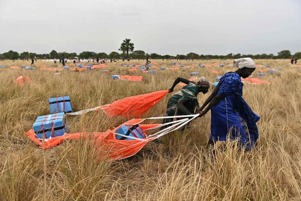 Villagers is south South Sudan collect food rations parachuted from a plane