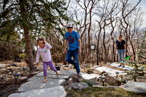 Evie Lewis, in purple pants and a pink T-shirt, is leading her parents, Elliot and Janell up on steps through a wooded area.