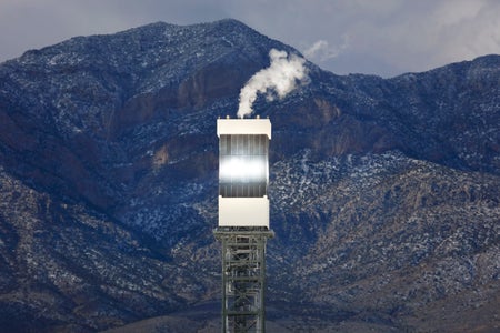 Sun reflects on tower of solar power generation tower in desert.