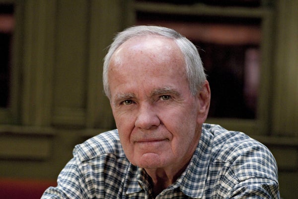 Shoulder-up portrait of Cormac McCarthy wearing plaid shirt, looking into camera.