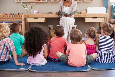 Teacher reads to a group of children sitting on the floor