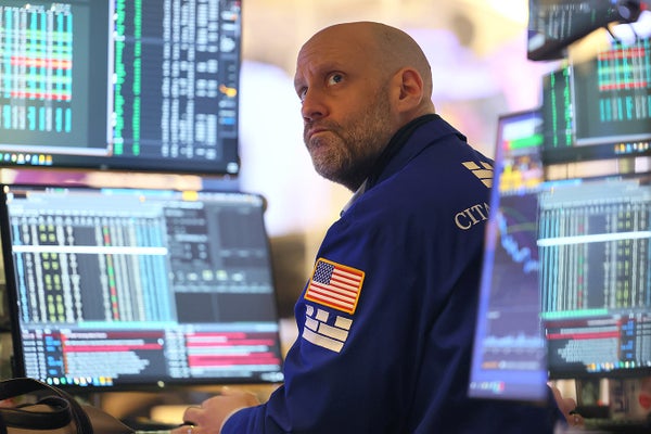 Trader looks over his shoulder away from multiple computer screens filled with data