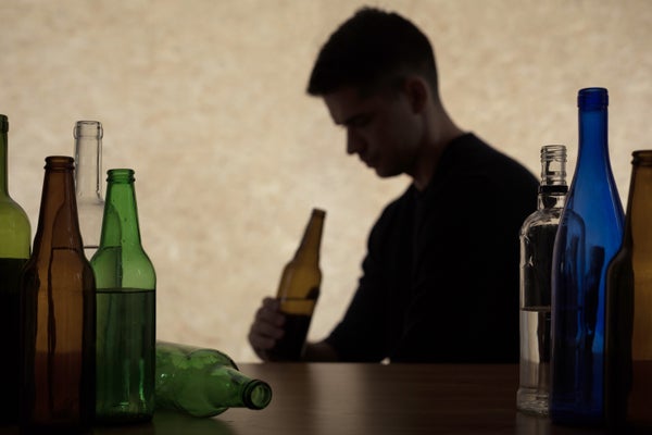 Silhouette of a teenager holding a beer bottle.