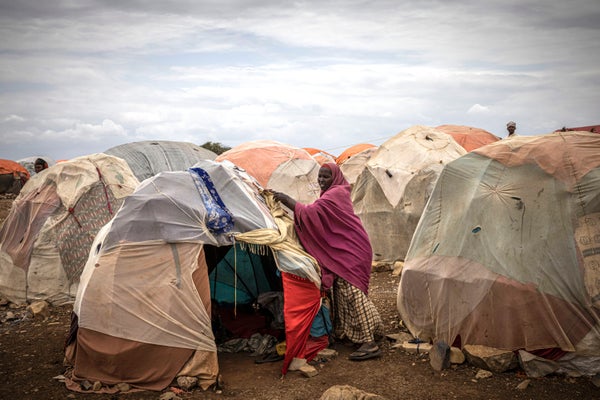 A woman in front of tents in a camp.