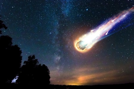 A comet falls to the Earth against a starry sky.