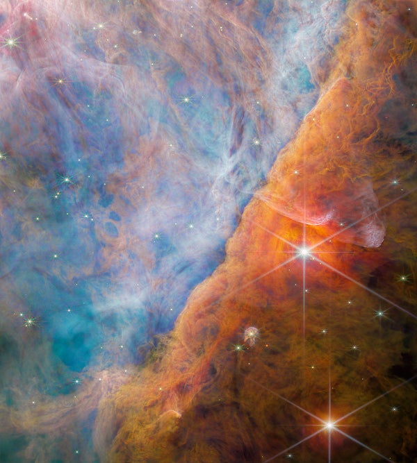 Billowy, multi-cloud spectacle spans the view with shifting hues from blues and translucent oranges on the left to vibrant orange, red, and brown on the right, featuring two bright stars with diffraction spikes.
