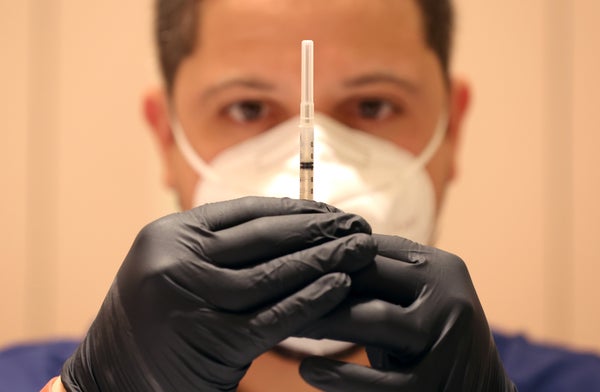 Healthcare working holding syringe in front of face