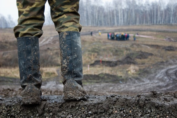 Person standing in tall muddy boots overlooking landscape