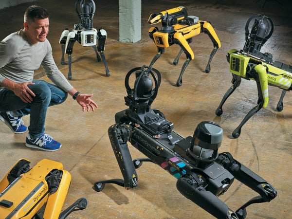 A man surrounded by multiple robot dogs.