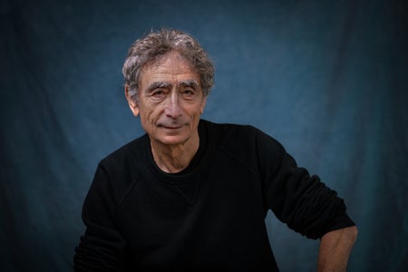 Bust portrait of a man in black shirt shown in front of a blue backdrop.