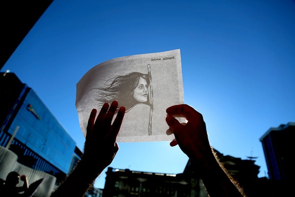 Woman holding photo of Iranian woman who dies under custody.