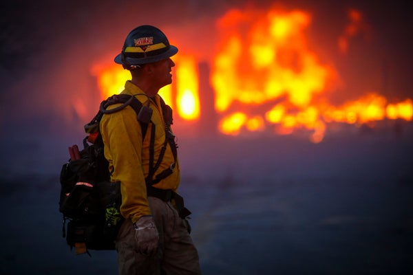 A firefighter close up in front of wildfire