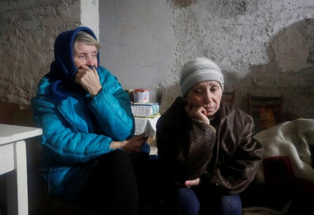 Two senior women seek refuge in a bomb shelter.