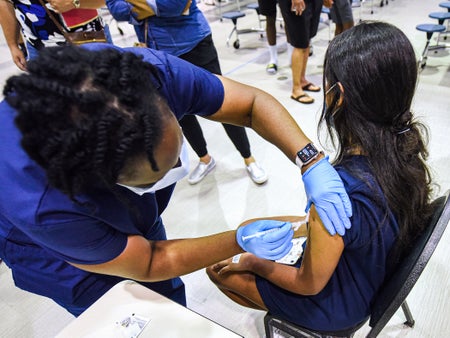 A nurse gives a girl a dose of the Pfizer vaccine at a COVID-19 vaccine clinic.