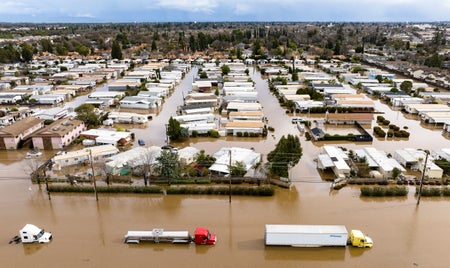 Flooded Homes with 2 trucks driving through flooded streets.