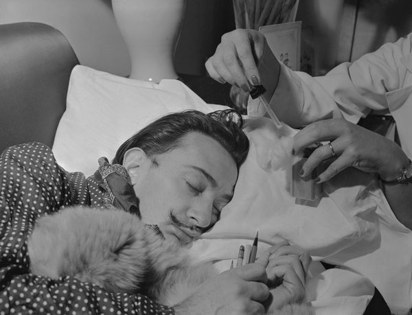 Salvador Dali sleeps as someone perfumes his pillow
