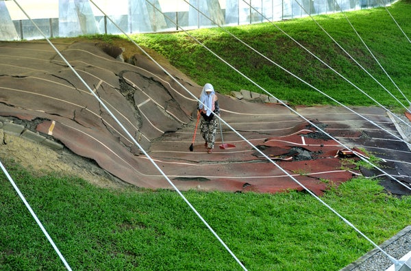 Worker sweeping damaged running track which is reserved as an earthquake park