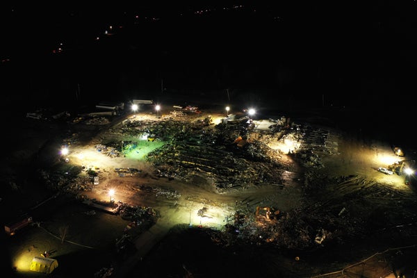 A lighted view at night of tornado damage in Mayfield, KY.
