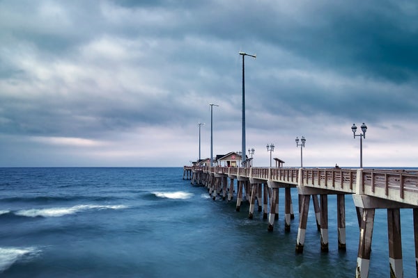 View of pier under moody blue skies.