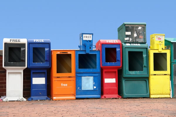 Various colorful, empty news racks in a row on a public sidewalk