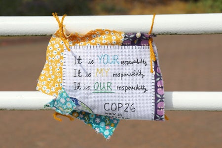 Embroidered sign hung on railing.
