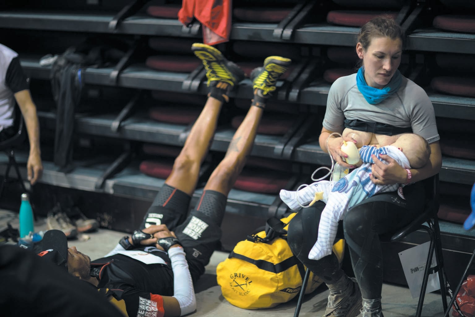 Woman sitting in a folding chair, breastfeeding an infant.