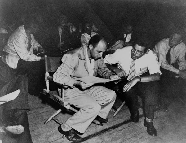 A black and white photo of men conferring while seated.