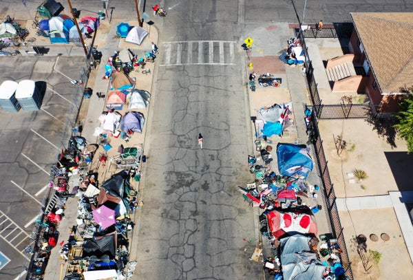 An aerial view of people and tents of a homeless encampment on either side of an Phoenix street.