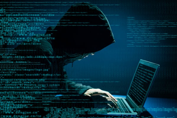 A hooded figure hunched over a computer.